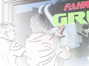 Fensterbeschriftung. 2 Mitarbeiter folieren das Fenster von Fahrschule Grün